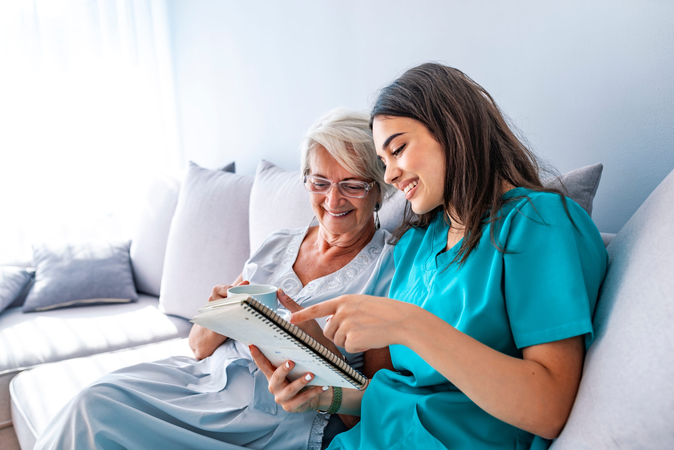 Young nurse spending time with happy elder patient in nursing home.